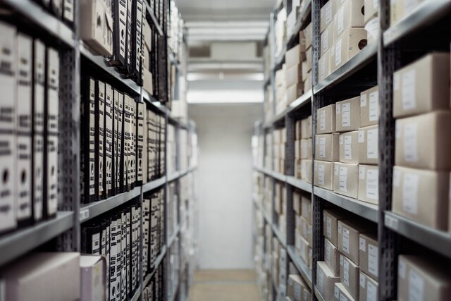 Rows of archive boxes and binders on storage shelves